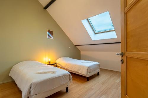 a attic room with two beds and a window at Le 48-GregIMMO-Appart'Hôtel in Montbéliard