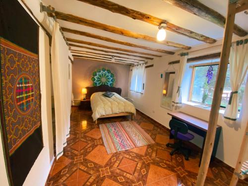 a bedroom with a bed and a desk in a room at Sonqo Andino Hospedaje Medicina - La Rinconada in Pisac