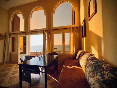 a living room with a couch and a table and windows at Dar diafa samira in Mirleft