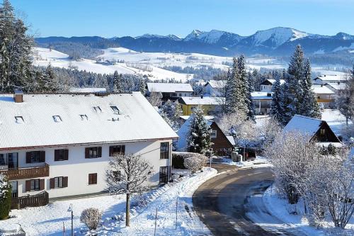un pueblo cubierto de nieve con montañas en el fondo en Ferienwohnung im Allgäu mit Bergsicht en Oberreute
