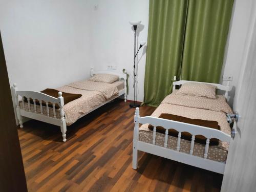 Habitación con 2 camas, cortinas verdes y suelo de madera. en BONACA - BAR, en Bar