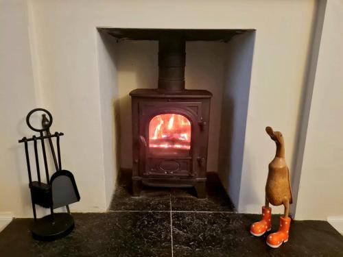 a wood stove in a room with a figurine in front of it at Old Tavern House in Fortrose