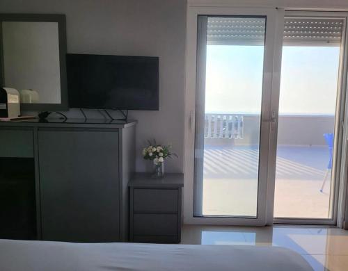 ein Schlafzimmer mit Bett, Fernseher und Balkon in der Unterkunft Vila Chelsea in Ksamil