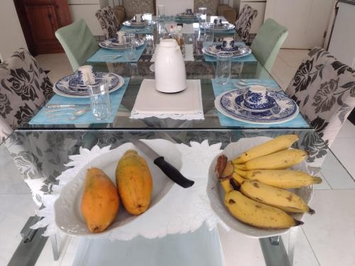 a glass table with plates of bananas and pears on it at POUSADA BELA VISTA in Pirenópolis