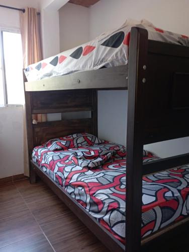 1 dormitorio con 2 literas y una manta colorida en Selva Maria Tayrona's Hostel, en Santa Marta