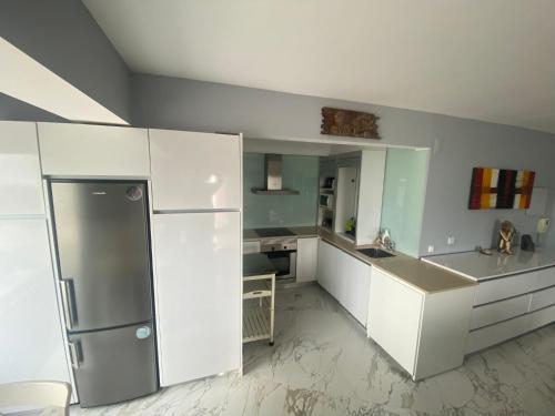 a kitchen with white cabinets and a stainless steel refrigerator at SEA FRONT in Armação de Pêra