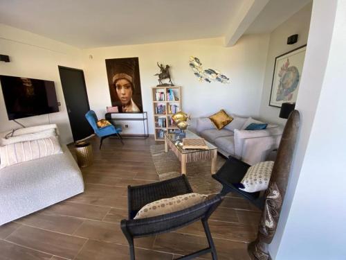 ein Wohnzimmer mit einem Sofa und Stühlen in der Unterkunft Le CAILLOU in La Trinité