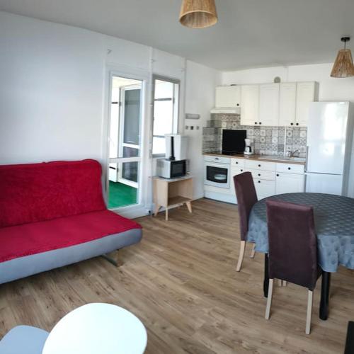 a living room with a red couch and a table at APPARTEMENT AVEC TERRASSE SUR LE PORT in Fécamp