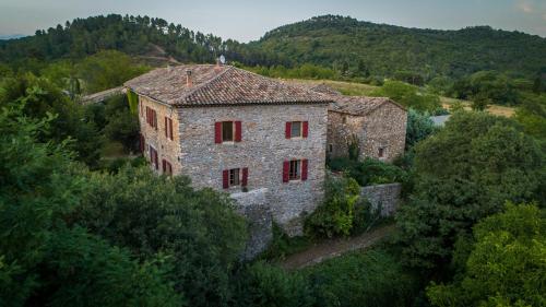 un vieux bâtiment en pierre avec des fenêtres rouges sur une colline dans l'établissement Le Mas de Roussa, à Meyrannes