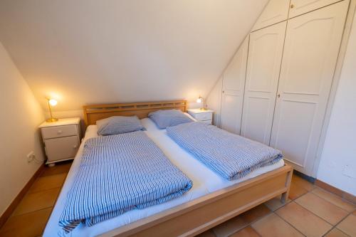 - une chambre avec un lit doté de draps bleus et de 2 tables de nuit dans l'établissement Ferienwohnung Brise, à Wyk auf Föhr