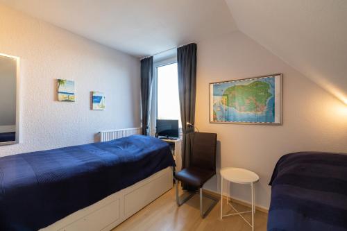 Schlafzimmer mit einem Bett, einem Schreibtisch und einem Fenster in der Unterkunft Ferienwohnung Südstrand in Wyk auf Föhr