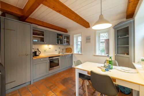 a kitchen with gray cabinets and a table with chairs at Ferienwohnung Oldsum in Oldsum