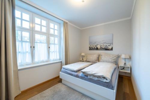 um quarto com uma cama e uma grande janela em Villa Friedericia, Wohnung 3-Hochparterre links em Wyk auf Föhr