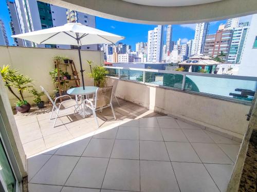 balcón con mesa, sillas y sombrilla en Apto centro com piscina, en Balneário Camboriú