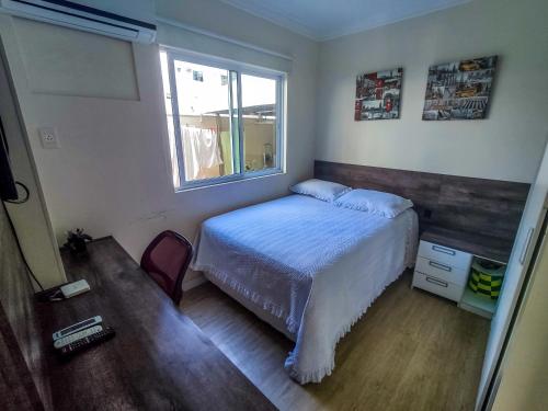 1 dormitorio con cama y ventana en Apto centro com piscina, en Balneário Camboriú