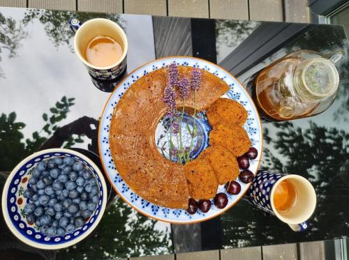 a table with a plate of food and a bowl of blueberries at Drewniany dom w brzozowisku in Pieszyce