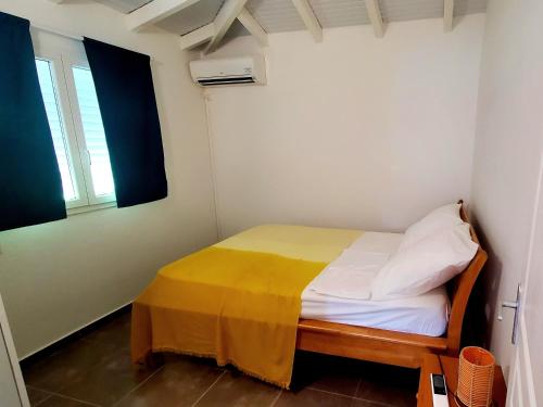 een kleine slaapkamer met een bed met een gele deken bij Saint Rose : Charmant T3 proche de la plage in Plessis-Nogent