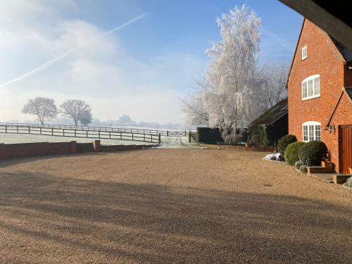 a brick building with a fence next to a road at Hillside Farm Barn in Woking