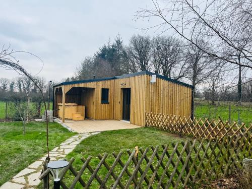 Bobital的住宿－Côté Jardin，一座带围栏的田野上的小型木结构建筑