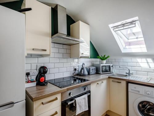 uma pequena cozinha com electrodomésticos brancos e uma janela em Modern Apartment in Central Lincoln em Lincoln