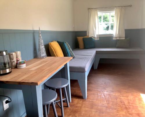 um quarto com um banco, uma mesa e uma janela em Greytown Campground em Greytown