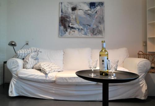 eine weiße Couch mit einer Flasche Wein auf dem Tisch in der Unterkunft Orka - Wijk de Brabander 93 in Cadzand
