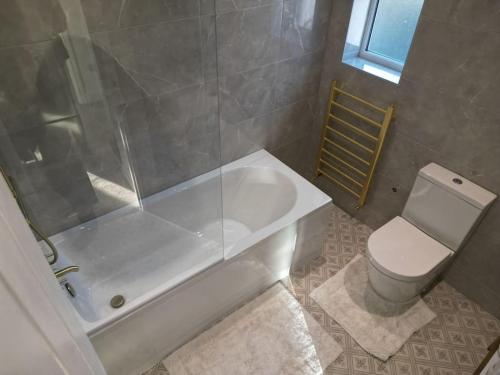 La salle de bains est pourvue d'une baignoire, de toilettes et d'une douche. dans l'établissement Homely & Peaceful Living Space, à Morden