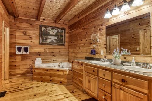 a log cabin bathroom with two sinks and a tub at Mountain Jewel, Game Room , Fire Pit, Theater Area, WIFI, Pool access!!! in Gatlinburg