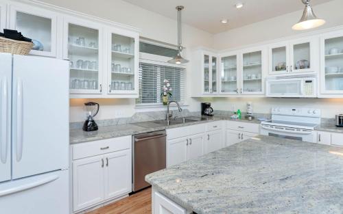 Una cocina con gabinetes blancos y encimeras de granito. en Pelican Roost 9407 home, en Gulf Highlands