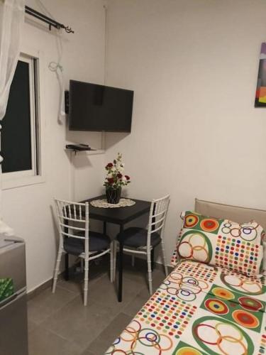 Cette petite chambre comprend une table, des chaises et une télévision. dans l'établissement Chambre américaine à Angondjé, à Libreville