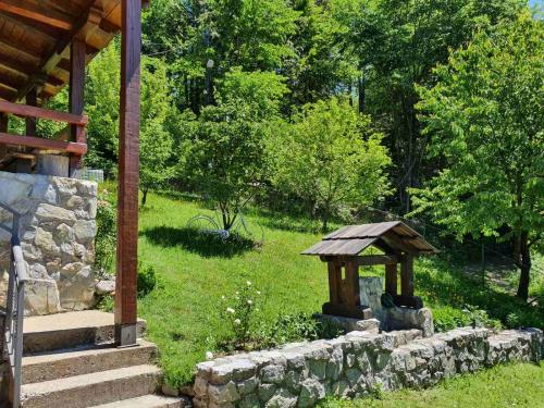a garden with a stone wall and a gazebo at Apartments Lux Labovic in Kolašin