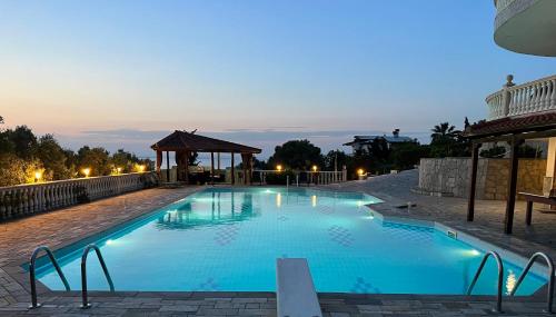 a large blue pool with a gazebo at night at El Paraiso Premium in Thessaloniki