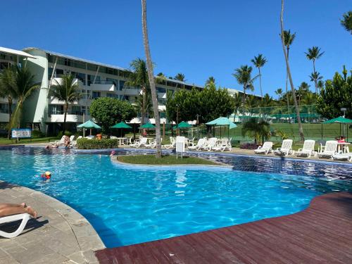 a swimming pool with chairs and umbrellas in a resort at Ancorar Flat in Porto De Galinhas