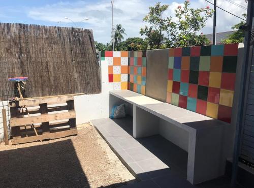 un banc assis à côté d'un mur coloré dans l'établissement Montabo duplex, à Cayenne