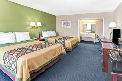 a hotel room with two beds and a television at Super 8 Carrollton in Carrollton