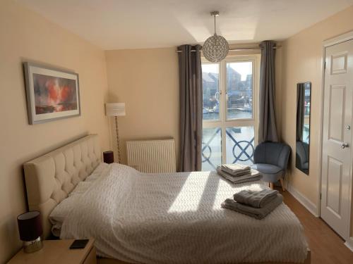 a bedroom with a bed and a chair and a window at Fabulously located Marina apartment - marina views in Pevensey