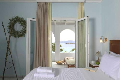 a bedroom with a bed and a view of the ocean at Aneroussa Beach Hotel in Batsi