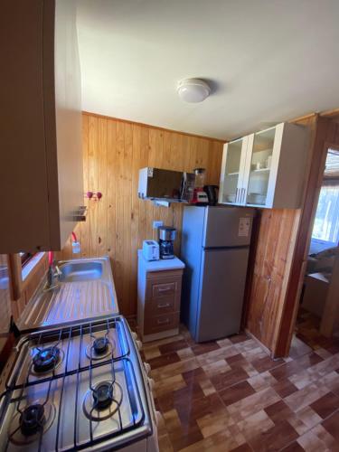 a kitchen with a stove and a refrigerator at Angel Cabaña in Villarrica