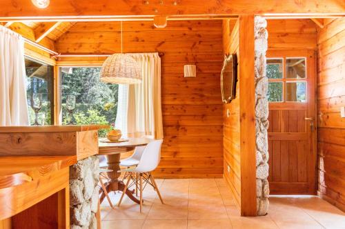 ein Esszimmer mit einem Tisch in einer Blockhütte in der Unterkunft BOG Jardin de Flores in Villa La Angostura