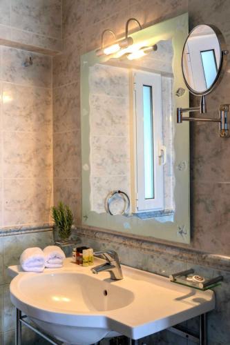 a bathroom with a sink and a mirror at Aneroussa Beach Hotel in Batsi