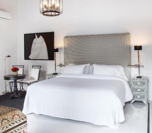 a bedroom with a large white bed and a table at Casa de la Renta By Mustique in Cartagena de Indias