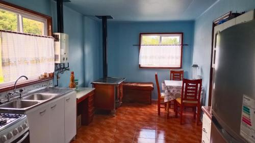 a kitchen with blue walls and a table and chairs at Casa Pangal Bajo in Puerto Aisén