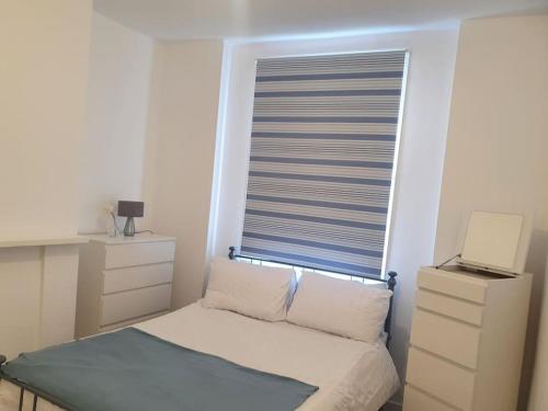 a small bedroom with a window with a bed and a desk at Spacious 5 bedroom House in South Norwood Croydon in Norwood