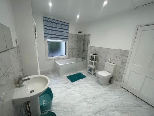 uma casa de banho com um lavatório, uma banheira e um WC. em Spacious 5 bedroom House in South Norwood Croydon em Norwood