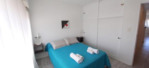 a room with a blue bed with towels on it at Enjoy Departamento Frente al Mar in Puerto Madryn