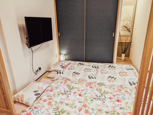 熊本的住宿－Spacious One Room Apartment for up to 5ppl w Kitchenette，卧室配有一张床,墙上配有电视。