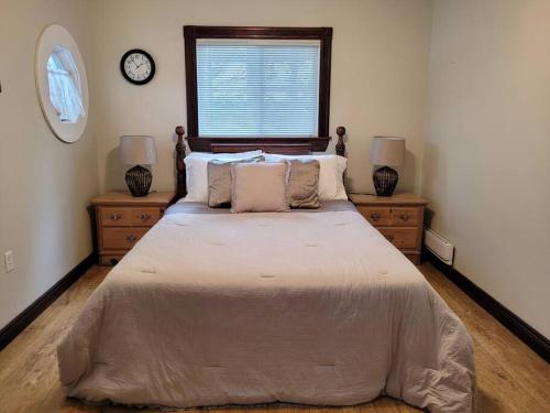 ein Schlafzimmer mit einem großen Bett mit zwei Kommoden und einem Fenster in der Unterkunft Rustic Pines Waterfront Cottage *CLEAR WATER* in Fenelon Falls