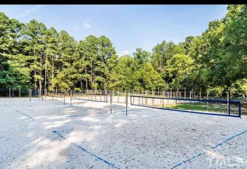 an empty tennis court with trees in the background at Lovely 2 Bedroom Condo with Pool in Chapel Hill