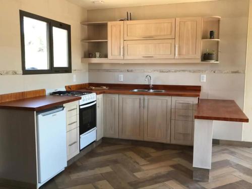 cocina con armarios de madera, fregadero y encimera en Cabana Villa Alpina en Villa Alpina