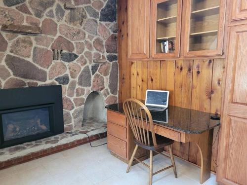 een bureau met een laptop in een kamer met een open haard bij Whispering Pines Riverside Retreat in Coboconk